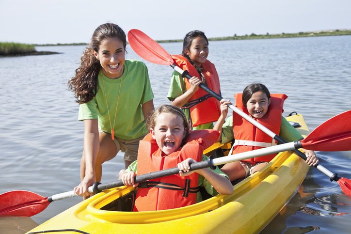 Teenage girl helping children in kayak
